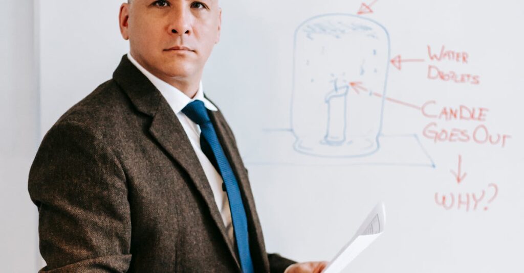 Man in formal attire presenting a scientific diagram on a whiteboard.